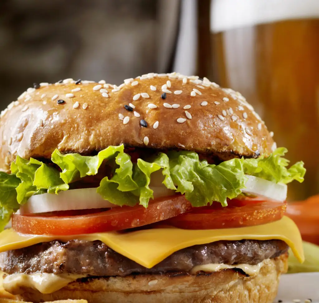 A hamburger with cheese, tomatoes and lettuce on it.